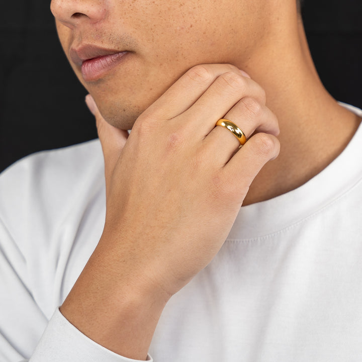 male model wearing a 24k gold wedding band on black background