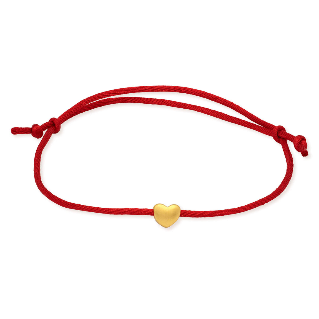 Red cord bracelet with a gold heart charm on a white background
